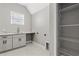 Laundry room with gray cabinets, white counters, utility sink, and closet with wire shelving at 5277 Epping Ln, Zephyrhills, FL 33541