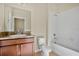 Bathroom with brown vanity, white tile shower, and toilet at 10751 Carloway Hills Dr, Wimauma, FL 33598