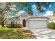 Charming single-story home with a red front door, attached garage, and landscaped yard at 27837 Sky Lake Cir, Wesley Chapel, FL 33544