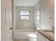 Bathroom with marble tile walls, white bathtub, toilet, and granite vanity at 2558 12Th S Ave, St Petersburg, FL 33712