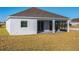 Back exterior of a single-story home with white siding, brown roof, screened porch, and grassy yard at 25494 Calusa Dr, Punta Gorda, FL 33955