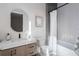 Contemporary bathroom with tiled tub/shower combo, round mirror, and wood vanity at 1046 Snell Isle Ne Blvd, St Petersburg, FL 33704