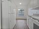 Compact kitchen with white appliances, wood-look flooring, and natural light at 2061 Willow Hammock Cir # 107, Punta Gorda, FL 33983