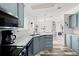 Bright, galley-style kitchen with gray cabinets, black appliances, and wood-look flooring at 4920 Sedeno Dr, Zephyrhills, FL 33541