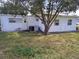 Back exterior view of a single-story home with a large tree and grassy yard at 105 Lake Tarpon Dr # 26, Palm Harbor, FL 34684