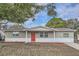 Updated one-story home with gray siding, red door, and landscaping at 11615 Meadow Dr, Port Richey, FL 34668
