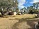 Large backyard with mature trees and partial house view at 12010 Villa Rd, Spring Hill, FL 34609