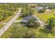 Aerial view of a modern style house with a dark roof surrounded by large trees and green lawns at 16760 Acapulco Rd, Punta Gorda, FL 33955