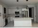 Modern kitchen with white cabinets, stainless steel appliances, white marble countertops and an island with hanging light fixtures at 16760 Acapulco Rd, Punta Gorda, FL 33955