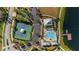 Aerial view of the community pool, tennis court, lake, and surrounding green spaces, with a parking lot nearby at 1570 Fox Grape Loop, Lutz, FL 33558