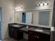Bathroom featuring double vanity with granite countertop, stylish lighting, and framed mirror at 1570 Fox Grape Loop, Lutz, FL 33558