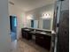Bright bathroom featuring double vanity with granite countertop and large mirror at 1570 Fox Grape Loop, Lutz, FL 33558