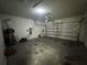 Empty two-car garage with white walls, a garage door, a lawn mower, and concrete flooring at 1570 Fox Grape Loop, Lutz, FL 33558