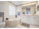 Bright bathroom featuring white cabinetry, neutral counters, and a standalone soaking tub for relaxation at 5923 Sandstone Ave, Sarasota, FL 34243