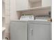 Functional laundry room equipped with a washer, dryer, and shelving for organized storage at 5923 Sandstone Ave, Sarasota, FL 34243