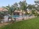 Fenced community pool surrounded by lush lawn and small palms at 1322 Pelican Creek Xing # B, St Petersburg, FL 33707