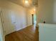 Hallway with wooden floors, white trim and doors, and ample natural light streaming through an open doorway at 7480 Aguila Dr, Sarasota, FL 34240
