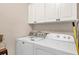 Well-lit laundry room with washer, dryer, and white storage cabinets at 7480 Aguila Dr, Sarasota, FL 34240