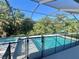 Screened pool area with a safety fence, spa, and a view of trees at 7480 Aguila Dr, Sarasota, FL 34240