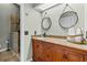 Bathroom with wood cabinet, granite countertop, round mirrors, and a glass door shower offering a modern, stylish space at 505 Sally Lee Dr, Ellenton, FL 34222