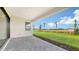 Covered patio with gray brick pavers overlooks a spacious grassy yard and landscaping at 14370 Hammock Oak St, Parrish, FL 34219