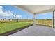 Covered patio with gray brick pavers overlooks a spacious grassy yard and landscaping at 14370 Hammock Oak St, Parrish, FL 34219