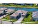 Overhead view of a home showcasing lush green lawn, a gray tile roof, and a brick driveway near a serene pond at 4621 Mondrian Ct, Sarasota, FL 34240