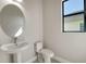 Bathroom featuring a pedestal sink, an oval mirror, and a toilet at 4621 Mondrian Ct, Sarasota, FL 34240