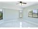 Spacious bedroom with sleek white marble floors, a ceiling fan, and multiple windows offering outdoor views at 1147 Yachtsman Ln, Punta Gorda, FL 33983