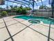Beautiful pool and spa area with a rock feature, offering a relaxing retreat in a screened enclosure at 2956 Laurel Ct, Dunedin, FL 34698