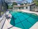 Stunning pool area enclosed with a screen, featuring a spa, rock waterfall, and serene backyard views at 2956 Laurel Ct, Dunedin, FL 34698
