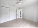 Bright bedroom with tiled floor, ceiling fan, closet, and view into an attached bathroom at 3593 Junction St, North Port, FL 34288