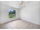 This is a bright bedroom with tiled floors, a ceiling fan, and a scenic view from its large window at 3593 Junction St, North Port, FL 34288