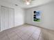 Bright bedroom with white walls, tiled floors, ceiling fan, and a window view of the outdoors at 3593 Junction St, North Port, FL 34288