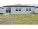 View of the home's rear, with a sliding glass door, windows, and a grassy lawn at 7744 Gilchrist Springs Dr, Parrish, FL 34219