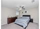 Cozy bedroom with a dark dresser, ceiling fan, and a comfortable bed with striped bedding at 13327 Willow Bluestar Loop, Riverview, FL 33579