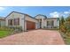 Beautiful single-story home with a red brick driveway, wood shutters, and a two-car garage at 14517 Coastal Woodland Ln, Parrish, FL 34219