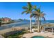 Waterfront property featuring manicured lawn, lush palm trees, private dock, and stunning bay views at 103 Shore Dr, Dunedin, FL 34698