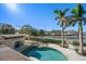 Waterfront property featuring a sparkling pool, lush palm trees, and stunning bay views at 103 Shore Dr, Dunedin, FL 34698