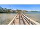 Long wooden dock leads out to beautiful bay waters, offering direct access for boating and water activities at 103 Shore Dr, Dunedin, FL 34698