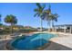 A beautiful backyard pool with a spa, pergola, travertine tile, and lush landscaping at 103 Shore Dr, Dunedin, FL 34698