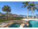 Backyard oasis featuring a pool, spa, travertine tile, and serene waterfront views at 103 Shore Dr, Dunedin, FL 34698