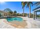 A sparkling pool surrounded by travertine tile, palm trees, and an outdoor pergola at 103 Shore Dr, Dunedin, FL 34698
