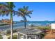 Waterfront property showcasing beautiful bay views, neighboring docks, lush palm trees, and outdoor pergola at 103 Shore Dr, Dunedin, FL 34698