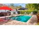 Backyard pool with patio and lounge seating under sun umbrellas, plus a well-manicured green hedge at 105 17Th Ne Ave, St Petersburg, FL 33704