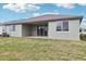Home's backyard with a covered patio, lush green grass, and a window at 1832 Draughton Dr, Zephyrhills, FL 33541