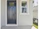 A close-up of a modern black front door with a window, complemented by gray siding and trim at 1852 Brekey Way, Zephyrhills, FL 33541