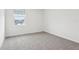 Carpeted bedroom showcasing a window and neutral walls with white baseboards at 1867 Draughton Dr, Zephyrhills, FL 33541