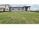 Spacious backyard featuring a gray exterior, large windows, and a covered patio for outdoor enjoyment at 1886 Draughton Dr, Zephyrhills, FL 33541