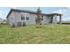 View of the home's backyard featuring a well-maintained lawn, modern siding, and a cozy covered patio at 1886 Draughton Dr, Zephyrhills, FL 33541